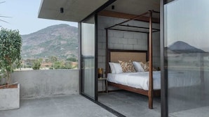 Ein Schlafzimmer mit Himmelbett, Blick auf einen Berg und einem Betonboden.