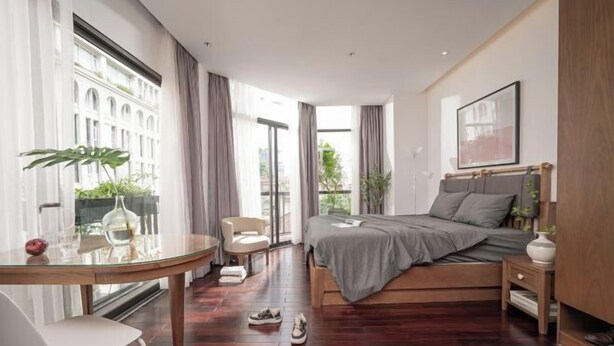 Une chambre moderne avec un lit, une table de chevet, une chaise et une table en verre ornée d’une plante.