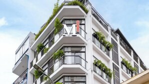 Un immeuble moderne à plusieurs étages, doté de balcons, d’un logo « M » bien visible et d’une enseigne indiquant qu’il s’agit d’un hôtel.