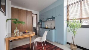 Une cuisine moderne avec des meubles de couleur bleu clair, une table à manger en bois et une chaise blanche, ainsi qu’une plante en pot.