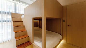 Un dormitorio con una cama litera, escalera de madera y un armario.