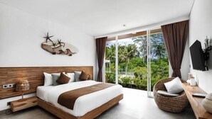Camera d'hotel moderna con un letto grande, una poltrona in vimini, una TV a schermo piatto e vista sul verde attraverso ampie finestre.