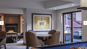 Een gezellige woonkamer met een open haard, een eethoek en een pooltafel.