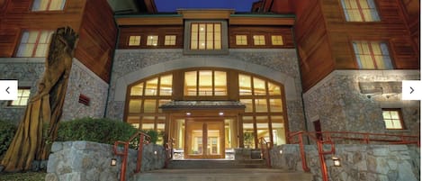 A multi-story building with a stone facade, large windows, and a central entrance with steps.