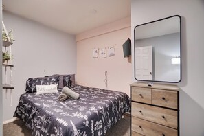 Une chambre à coucher comprenant un lit, une commode, un miroir, des éléments de décoration murale et une plante.