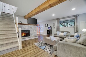 Ein modernes Wohnzimmer mit Kamin, einer Treppe, einer Sofagarnitur und Blick auf eine Treppe durch ein Fenster.