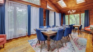 A wooden cabin with a dining area featuring a table set for six, blue chairs, and a chandelier. - Gloria's Hot Tub Game Room Fire Pit (Blakeslee)