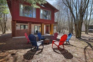 Une cabane à deux étages avec une terrasse, entourée d’arbres.