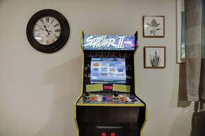 Ein altes Arcade-Spielgerät mit Bildschirm, einer Uhr und gerahmten Pflanzenillustrationen an der Wand.