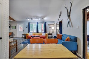 Een woonkamer met een houten tafel, twee banken en een raam met gordijnen.