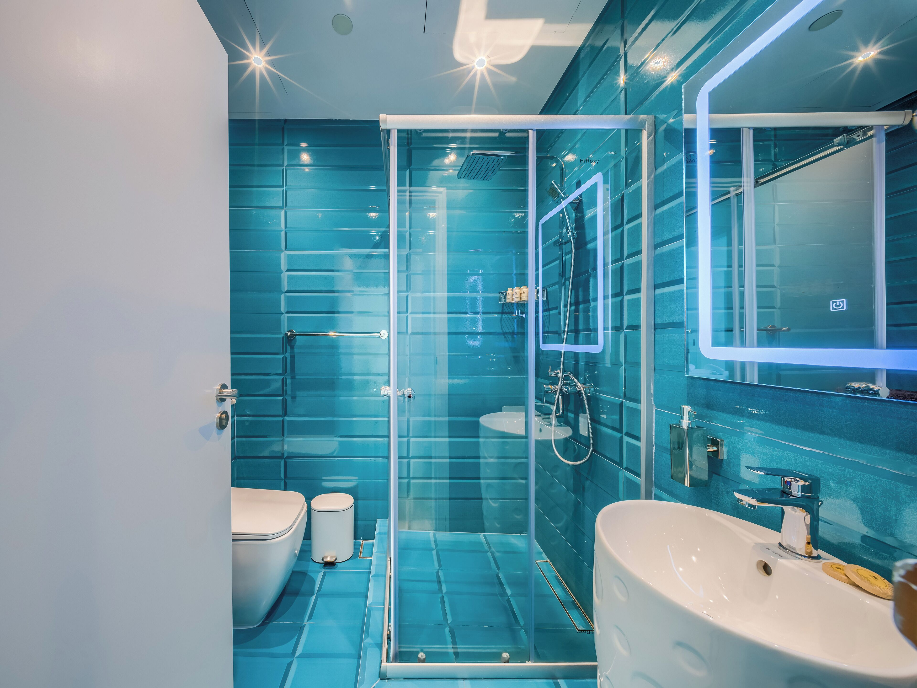 A modern bathroom with a glass shower enclosure, a white sink, and a toilet.