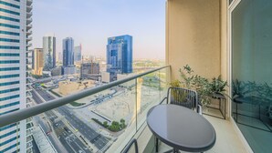 Varanda com mesa e cadeiras, vista para paisagem urbana com edifícios modernos e rodovia.