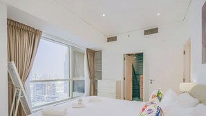 Quarto de hotel moderno com uma cama grande, vista para a cidade, varanda e um guarda-roupa.