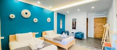 A modern hotel room with two beds, a blue accent wall, and a wooden floor.