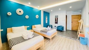 Een hotelkamer met twee bedden, een blauwe accentmuur en een houten vloer.