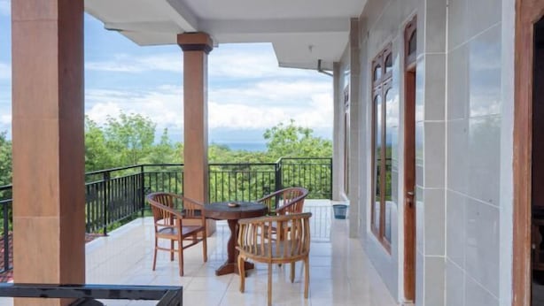 A balcony with a table and chairs, overlooking a scenic view. - SDK Homestay Uluwatu RedPartner (Bali)