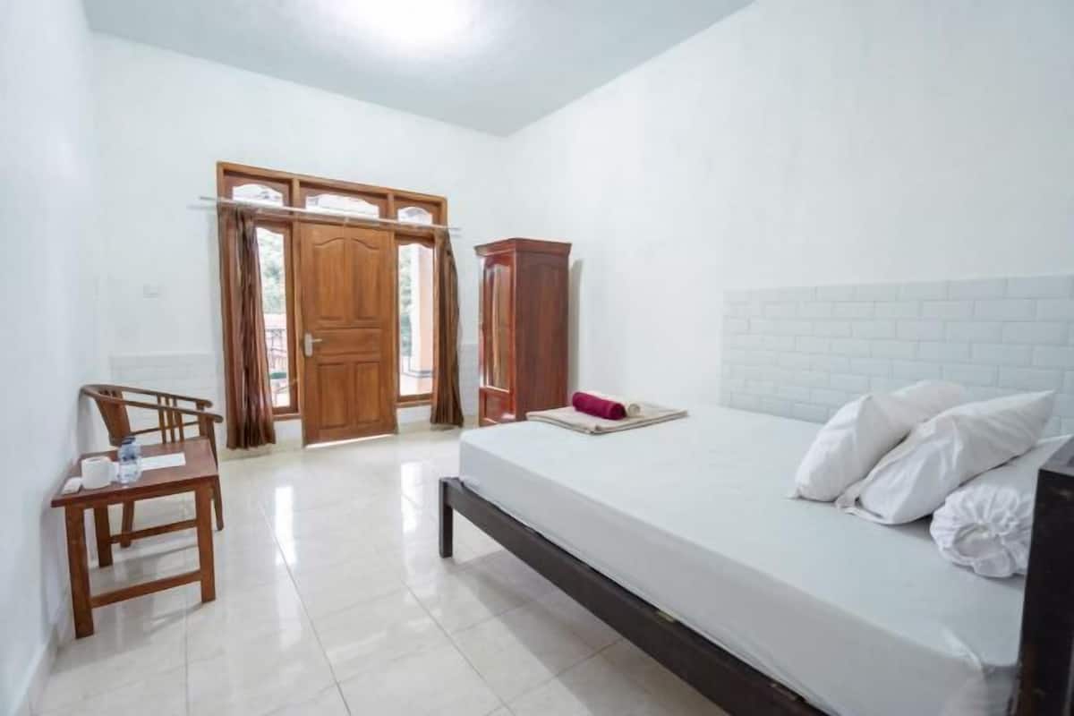 A room with a bed, a wooden chair, a small table, and a wardrobe.