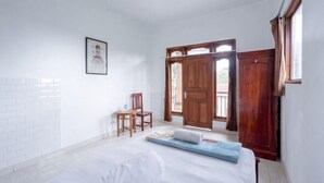 A bedroom with a bed, a chair, a wooden door, and a window. - SDK Homestay Uluwatu RedPartner (Bali)