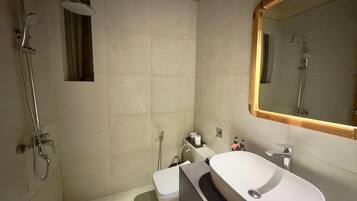 A modern bathroom with a shower, toilet, and sink.
