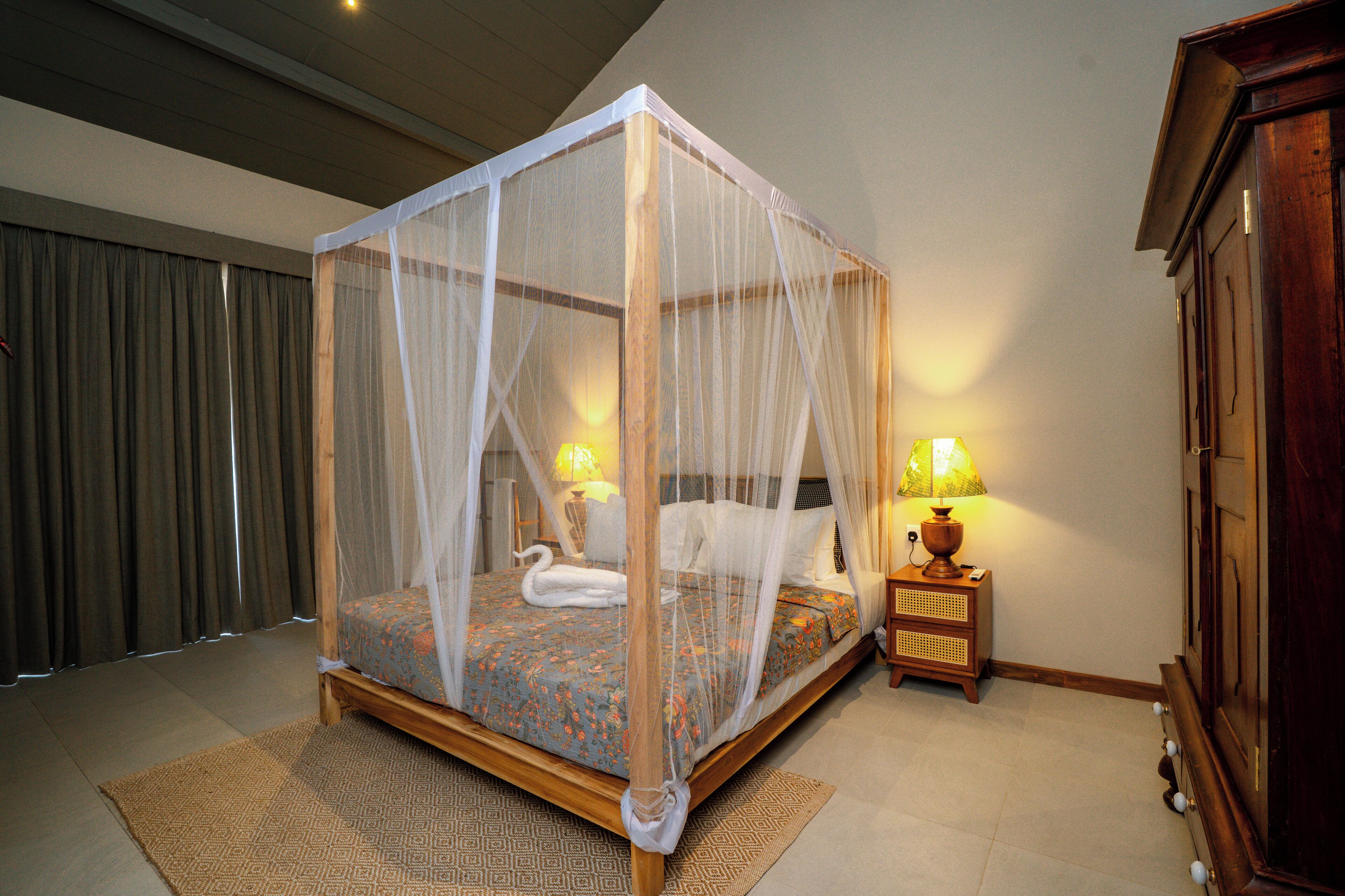 Un letto a baldacchino con tenda, un comodino con lampada e un armadio in legno.