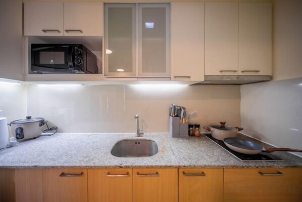 A kitchen with a microwave, toaster, sink, and cabinets. - WY Suites (Lapu-Lapu City)