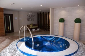 Un bain à remous dans une pièce dotée d’un plancher en bois, d’un canapé et d’un mur décoratif.