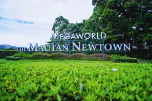 Une enseigne indiquant « Megaworld The Macan Newtown », avec une pelouse verdoyante et des arbres en arrière-plan.