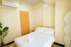A hotel room with a bed, a wardrobe, a bedside table, and a potted plant. - WY Suites (Lapu-Lapu City)