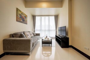 A modern living room with a sofa, a coffee table, and a television. - WY Suites (Lapu-Lapu City)