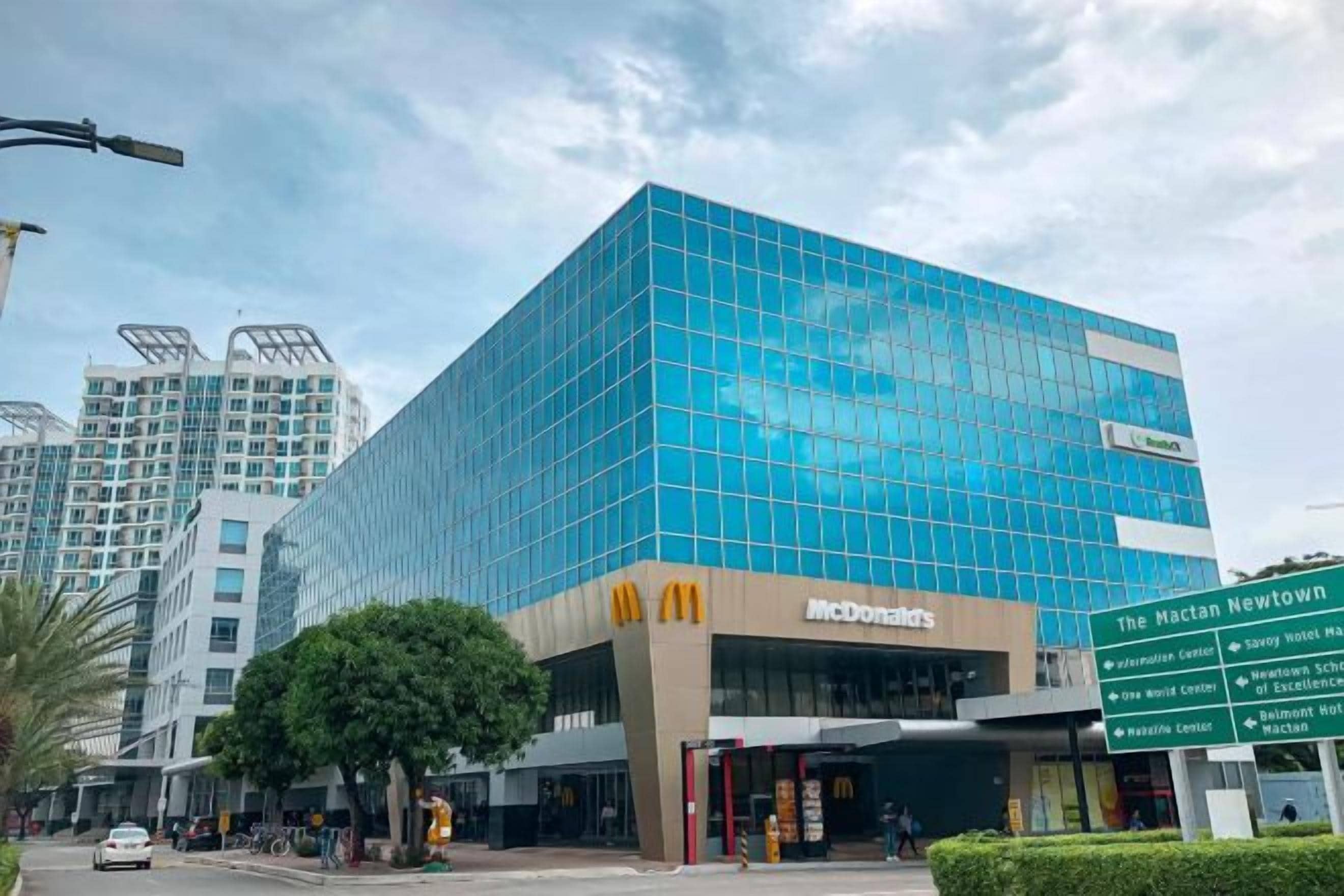 Ein modernes Gebäude mit Glasfassade und einem McDonald's-Schild, umgeben von städtischer Infrastruktur.