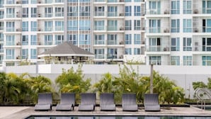 Un hôtel moderne doté d’un espace piscine, comprenant des chaises longues et un coin salon abrité.