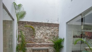 A swimming pool with stone walls, potted plants, and a metal pool ladder.