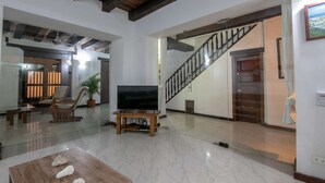 A spacious living room with a large TV, a wooden coffee table, and a staircase.