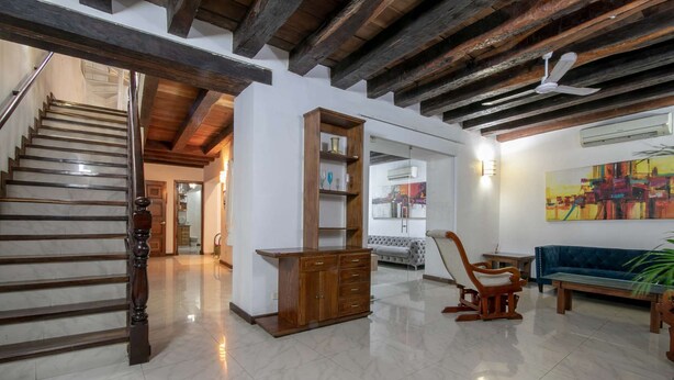 A spacious living area with a wooden staircase, a large wooden cabinet, a sofa, and a ceiling fan.