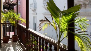 A balcony with potted plants and a view of a building with balconies and ornate details.