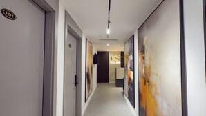 A modern hotel corridor with a reception area, numbered doors, and abstract art on the walls. - ES Hotel (Kashar)