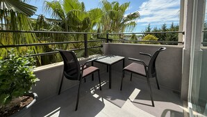 A balcony with a table and chairs, surrounded by lush greenery and a clear sky. - ES Hotel (Kashar)