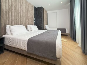 Una habitación de hotel moderna con una cama grande, una cama más pequeña y un área de descanso.