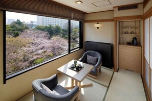 A room with a view of cherry blossoms, a sofa, a table with a tray, and a cabinet with glasses. - Takanawa Hanakohro, a Member of Small Luxury Hotels of the World (Tokyo)