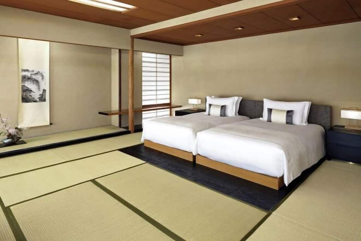 A traditional Japanese-style bedroom with tatami flooring, a double bed, and a sliding shoji screen.