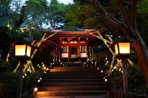 A traditional Japanese structure with a staircase leading up to a covered area, surrounded by trees and illuminated by lanterns. - Takanawa Hanakohro, a Member of Small Luxury Hotels of the World (Tokyo)