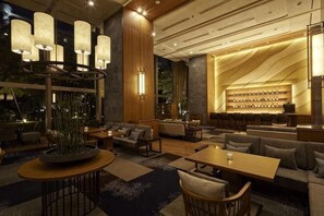 A spacious lobby with a seating area, a bar, and a large window.