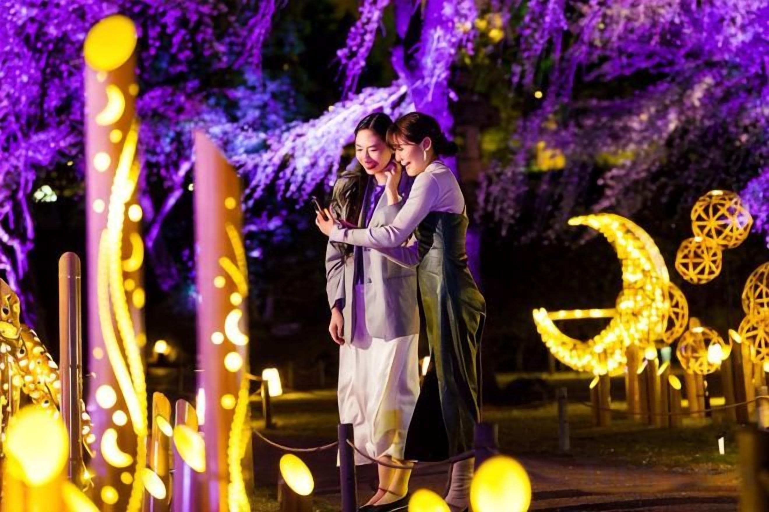 Two people embracing in a decorated outdoor area with illuminated structures.