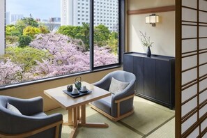 A room with a view of cherry blossoms, a sofa, a table with a teapot, and a cabinet. - Takanawa Hanakohro, a Member of Small Luxury Hotels of the World (Tokyo)