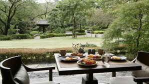 A table set outdoors with food and drinks, surrounded by greenery and a traditional building in the background. - Takanawa Hanakohro, a Member of Small Luxury Hotels of the World (Tokyo)