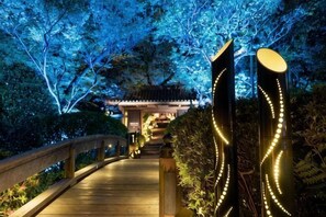 Un sentier menant à un bâtiment traditionnel, avec un pont en bois et des décorations illuminées.
