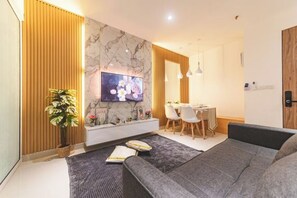 A modern living room with a sofa, TV, dining area, and a potted plant. - Beautiful Suites Seaview @ The Shore Kota Kinabalu (Kota Kinabalu)