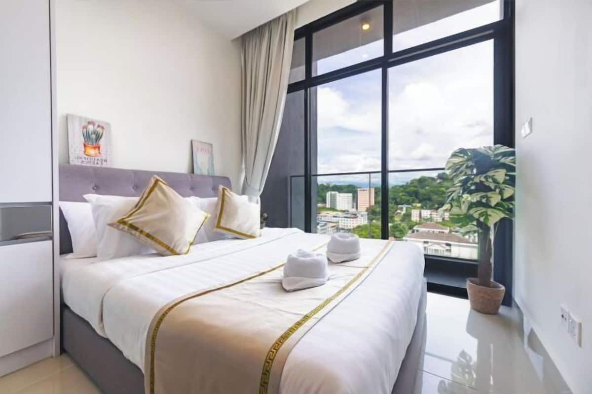 Ein Hotelzimmer mit einem großen Bett, Blick auf die Stadt und einer Zimmerpflanze.