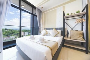 Ein Hotelzimmer mit einem großen Bett, Stadtblick, einem Balkon und einem Kleiderschrank mit Kleidung.