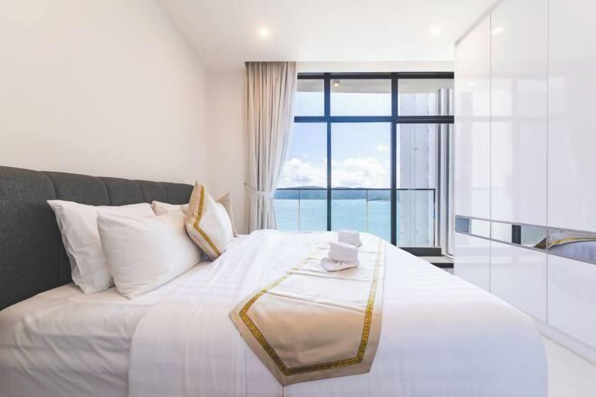 Ein Hotelzimmer mit einem großen Bett, Meerblick und einem Balkon.